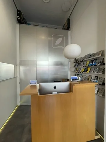 Interior de Santifer iRepair — lo que ve el cliente al entrar: mostrador con iMac, logo y lámpara esférica